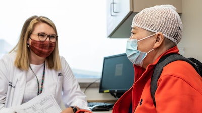 Patient Siyun Huang, right, wears an Optune device while talking with University of Cincinnati clinical research professional Alexis Brenner, left.