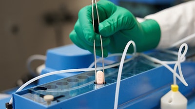 In this photo provided by Pfizer, a technician handles one of the company's COVID-19 Paxlovid pills. COVID-19 patients have two new treatment options that can be taken at home. But that convenience comes with a catch: The pills have to be taken as soon as possible once symptoms appear. U.S. regulators authorized the pills from Pfizer and Merck late 2021.