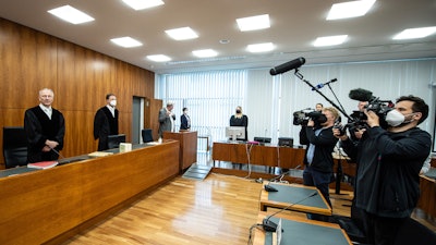 Volker Muetze (l), presiding judge at the Regional Court, stands in the courtroom for the opening in Kassel, HGermany, Wednesday, May 25, 2022. A German court on Wednesday sentenced a woman who posed as a fake doctor and caused the deaths of several of people to life imprisonment for three counts of murder, among other charges.