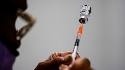 A syringe is prepared with the Pfizer COVID-19 vaccine at a vaccination clinic at the Keystone First Wellness Center in Chester, Pa., Dec. 15, 2021. Pfizer says tweaking its COVID-19 vaccine to better target the omicron variant is safe and boosts protection. Saturday, June 25, 2022 announcement comes just days before regulators debate whether to offer Americans updated booster shots this fall.