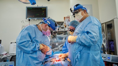 In this photo provided by NYU Langone Health, Dr. Nader Moazami, right, and cardiothoracic physician assistant Amanda Merrifield, center, and other members of a surgical team prepare for the transplant of a genetically modified pig heart into a recently deceased donor at NYU Langone Health on Wednesday, July 6, 2022, in New York. Experiments are raising new hope that pigs might one day help fill a shortage of donated organs -- at least, for people who need a new heart or kidney.