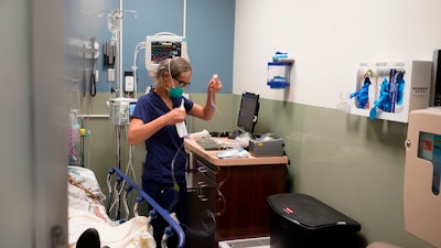 Registered nurse Sandra Younan sets up a new intravenous line for a patient under her care at Providence Cedars-Sinai Tarzana Medical Center in Los Angeles on March 11, 2021. California officials, on Tuesday, July 19, 2022, announced health insurance rates would increase an average of 6% for the 1.7 million people who purchase coverage through the state run health insurance marketplace, Covered California. Health insurers in individual marketplaces across 13 states and Washington D.C. will raise rates an average of 10% next year.