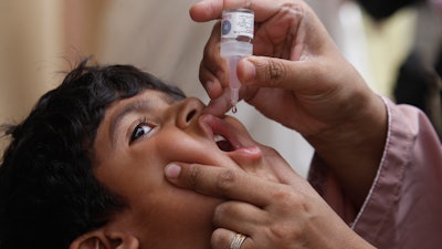 A health worker gives a polio vaccine to a child in Karachi, Pakistan, May 23, 2022. British health authorities on Wednesday, Aug. 10 say they will offer a polio booster dose to children aged 1 to 9 in London, after finding evidence the virus has been spreading in multiple regions of the capital, despite not confirming any cases of the paralytic disease in people.