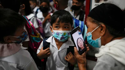 A boy talks to his mother from a smartphone during the opening of classes at the San Juan Elementary School in metro Manila, Philippines on Monday, Aug. 22, 2022. Millions of students wearing face masks streamed back to grade and high schools across the Philippines Monday in their first in-person classes after two years of coronavirus lockdowns that are feared to have worsened one of the world's most alarming illiteracy rates among children.