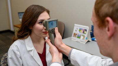 A staff member in Georgina Lynch’s lab at the Washington State University Spokane campus demonstrates the use of a handheld monocular pupillometer to measure the pupillary light reflex.