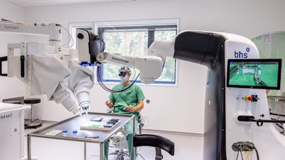 Dr. Maximilian Kückelhaus presents the new method in a dry-run training session. The operations robot (right) is networked with a robotic microscope (left).