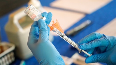 A nurse prepares a syringe of a COVID-19 vaccine at an inoculation station in Jackson, Miss., Tuesday, July 19, 2022. On Thursday, Oct. 20, 2022, a panel of U.S. vaccine experts said COVID-19 shots should be added to the lists of recommended vaccinations for kids and adults.
