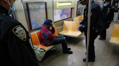 New York Police Department officers wake up sleeping passengers and direct them to the exits at the 207th Street station on the A train, Thursday, April 30, 2020, in the Manhattan borough of New York.