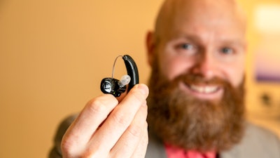 Sterling Sheffield, an assistant professor of Speech, Language, and Hearing Sciences at the University of Florida, holds an over-the-counter hearing aid Wednesday, Nov. 30, 2022, in Gainesville, Fla.