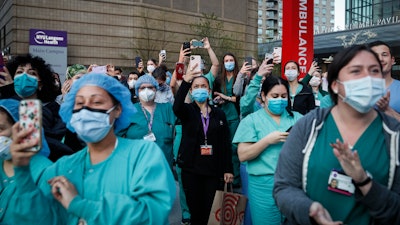 In this April 28, 2020, file photo Medical personnel attend a daily 7 p.m. applause in their honor outside NYU Langone Medical Center in New York.