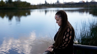 Moonlight Pulido stands by the shore at Harbor Lake Wednesday, Dec. 7, 2022, in Los Angeles. California is paying reparations to victims, mostly women, who were either forcibly or coercively sterilized by the government. Pulido was sterilized while incarcerated in 2005.