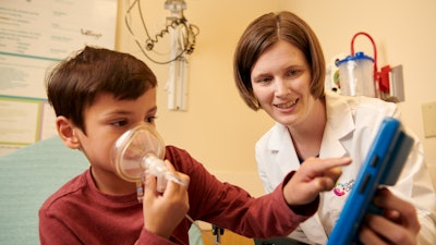 Cincinnati Children’s nurse practitioner Abby Hess, right, came up with the idea for a video game to help young kids relax when it’s time to put on an anesthesia mask before surgery. Ethan Stallsworth, a patient at Cincinnati Children's, demonstrates how the game works.