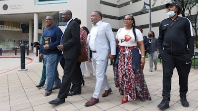 Attorney Ben Crump, second from left, walks with Ron Lacks, left, Alfred Lacks Carter, third from left, both grandsons of Henrietta Lacks, and other descendants of Lacks, outside the federal courthouse in Baltimore, Oct. 4, 2021.