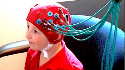 A young study participant wears a functional Near Infrared Spectroscopy system cap, which allows neuro scientists to measure brain activity by monitoring changes in blood flow in the brain.