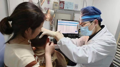 In this photo provided by researchers in January 2024, Dr. Yilai Shu examines a young patient at the Eye & ENT Hospital of Fudan University in Shanghai, China, after a gene therapy procedure for hereditary deafness.