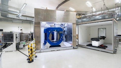 Beam line of the proton therapy system (left) with opened Aurora-PT system (i.e. in-beam MRI (middle) and patient couch (right).