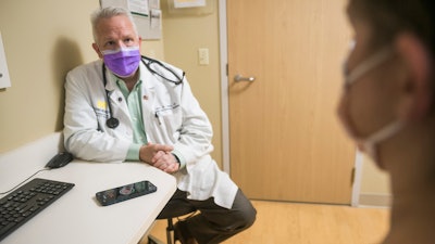 In this photo provided by University of Michigan Health-West, Dr. Lance Owens, chief medical information officer at the university, demonstrates the use of an AI tool on a smartphone in Wyoming, Mich., on Sept. 9, 2021. The software listens to a doctor-patient conversation, documents and organizes it to write a clinical note.