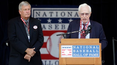 Dr. Frank Jobe, right, known for the development of the historic elbow procedure known as 'Tommy John Surgery,' speaks as he and Tommy John, left, are honored during a ceremony at Doubleday Field at the National Baseball Hall of Fame in Cooperstown, N.Y. , July 27, 2013.