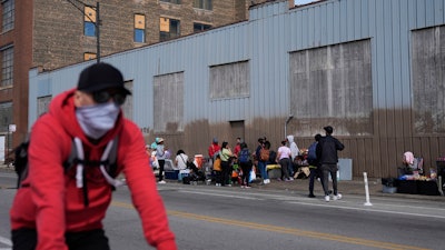 People hang around outside of a migrant shelter Wednesday, March 13, 2024, in the Pilsen neighborhood of Chicago. Multiple people living at the shelter for migrants have tested positive for measles since last week. A team from the Centers for Disease Control and Prevention is supporting local officials' response.