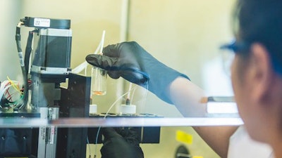 Miji Yeo, a postdoctoral researcher at Penn State, checks the bioink cartridges on a 3D printer developed to intraoperatively print layers of skin.