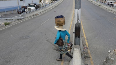 A street vendor crosses a street that is empty due to residents staying home amid gang violence in Port-au-Prince, Haiti, Monday, April 8, 2024.