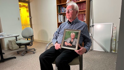 Michael Kruzich holds a photo of his late mother Donna during an interview Monday, April 15, 2024, in Lansing, Mich. Donna Kruzich was one of dozens of people in the U.S. who died after being injected with tainted steroids made by a specialty pharmacy in Massachusetts. Now, more than a decade later, the operator of the New England Compounding Center is returning to a Michigan court to be sentenced on involuntary manslaughter charges.