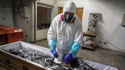 An employee takes the fingerprints of a woman who died from the new coronavirus before her remains are cremated at La Recoleta crematorium in Santiago, Chile, Saturday, June 27, 2020. Countries are still struggling to come up with an agreed-upon plan for how the world might respond to the next global outbreak. A ninth and final round of talks involving governments, advocacy groups and others to finalize a “pandemic treaty” is scheduled to end Friday, May 10, 2024.