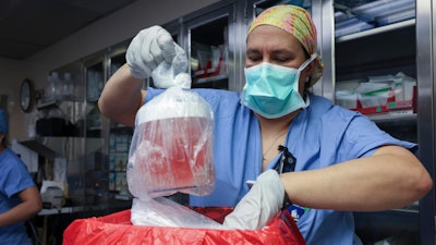 Melissa Mattola-Kiatos, RN, nursing practice specialist, removes the pig kidney from its box to prepare for transplantation at Massachusetts General Hospital, March 16, 2024, in Boston. Richard “Rick” Slayman, the first recipient of a genetically modified pig kidney transplant, has died nearly two months after he underwent the procedure, his family and the hospital that performed the surgery said Saturday, May 11.