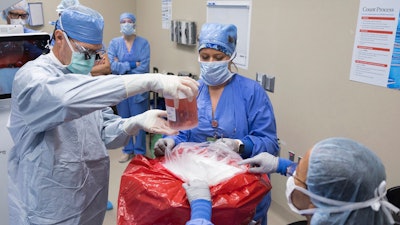 In this photo provided by the Mayo Clinic, Dr. David Lott, Mayo Clinic’s chair of head and neck surgery, lifts the donor organ out of a perfusion container at Mayo Clinic Hospital in Phoenix, on Feb. 29, 2024. Marty Kedian regained his voice after surgeons removed his cancerous larynx and, in a pioneering move, immediately replaced it with a donated one.