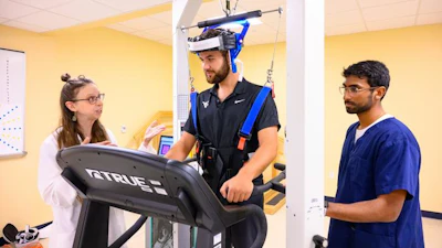 Julie Brefczynski-Lewis (left), a research assistant professor in the WVU School Medicine, and students Colson Glover (center) and Nanda K. Siva conduct a walking PET scan demonstration at WVU Health Sciences.