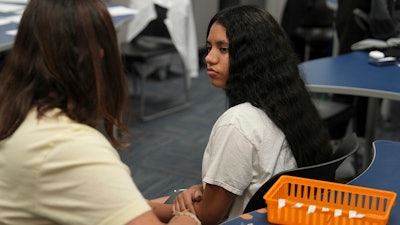 Chanel Ferran Gutierrez, a 10th grade student at Newcomer Academy, prepares to be vaccinated during a pop-up immunization clinic in the school's library in Louisville, Ky., on Thursday, Aug. 8, 2024.