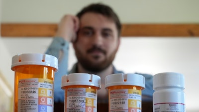 Cancer patient Steven Manetta sits for a portrait Monday, Sept. 9, 2024, in his Lemont, Ill., home with four of the five medicines he takes daily to battle the nausea from his chemotherapy.