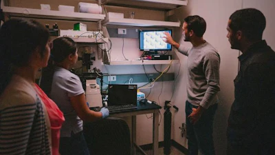 Seth Cordts, a Tang lab PhD student, and other lab members study a microscope image of the microGrater. This new tool and its counterpart — the microDicer — will allow researchers to improve the consistency and quality of tumor samples, which have direct impact on the quality of the data from downstream experiments such as measurements of drug response.