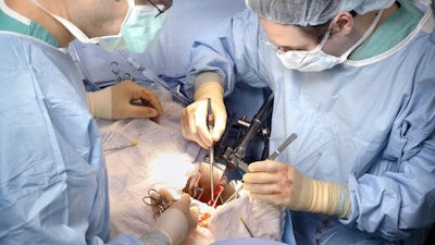 In this photo provided by Johns Hopkins Medicine, Dr. Dorry Segev, right, performs the first U.S. transplant of a kidney from a deceased donor who had HIV into a recipient living with HIV, in Baltimore, in March 2016.