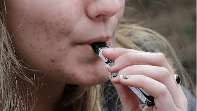 A high school student uses a vaping device near a school campus in Cambridge, Mass., April 11, 2018.