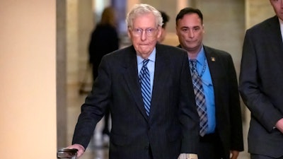 Senate Minority Leader Mitch McConnell of Ky., left, wears a bandage on his face and wrist as he walks to cast a vote on the Senate floor after falling during a luncheon on Capitol Hill, Tuesday, Dec. 10, 2024, in Washington.
