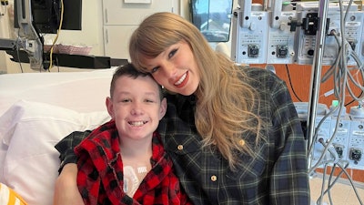 In this image provided by Cassie Thomas, Beckett Thomas, 13, who is a patient at Children's Mercy Hospital in Kansas City, Mo., poses with Taylor Swift, Thursday, Dec. 12, 2024.
