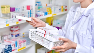 A pharmacist refills shelves at a drug store.