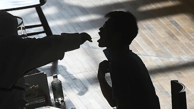 A medical worker takes a swab sample from a worker of the China Star Optoelectronics Technology (CSOT) company during a round of COVID-19 tests in Wuhan in central China's Hubei province, Aug. 5, 2021.