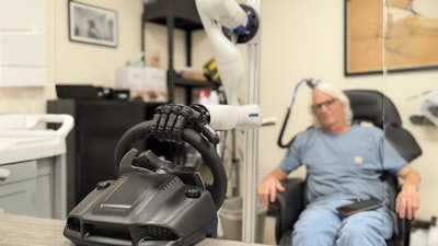 A testing participant controls a bionic hand through a brain-computer interface that allows him to feel pressure changes as the steering wheel moves in the hand.