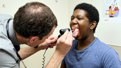 Dr. Joshua Williams, a pediatrician whose federal funding for a vaccine awareness program was cut, examines 12-year-old patient Tiovian Darden in Denver on Tuesday, March 18, 2025.