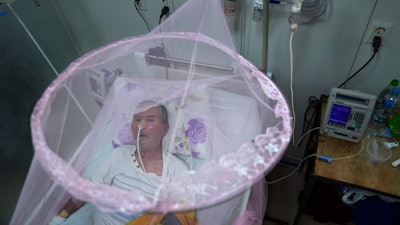 A patient infected with chikungunya looks out from mosquito netting at the Clinicas Hospital in San Lorenzo, Paraguay, Friday, March 3, 2023.