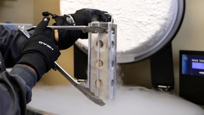 A container with frozen embryos and sperm stored in liquid nitrogen is removed at a fertility clinic in Fort Myers, Fla., Oct. 2, 2018.