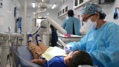 A dentist cleans the teeth of a child in the public health department’s mobile dental clinic visiting Starmount Elementary school in Charlotte, N.C., on March 20, 2025.