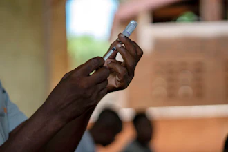 Dark-skinned hand preparing a medical injection or vaccine