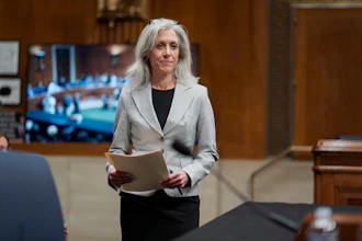 Professional woman in gray blazer holding document in formal hearing room