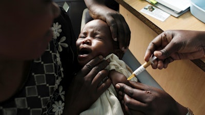 A mother holds her baby receiving a new malaria vaccine as part of a trial at the Walter Reed Project Research Center in Kombewa in Western Kenya on Oct. 30, 2009.