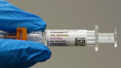 A pharmacist holds a Pfizer and BioNTech COVID-19 vaccine shot on Thursday, April 24, 2025, in Portland, Ore.