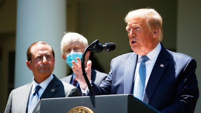President Donald Trump speaks about the coronavirus in the Rose Garden of the White House, May 15, 2020, in Washington. Department of Health and Human Services Secretary Alex Azar, left, and Dr. Robert Redfield, director of the Centers for Disease Control and Prevention listen.