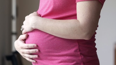 A pregnant woman stands for a portrait in Dallas, May 18, 2023.